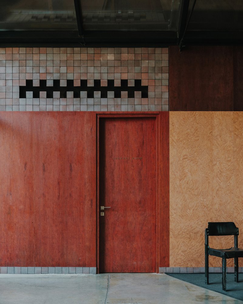 Red plywood door with mosaic tile clerestory band and adjacent plywood wall panel