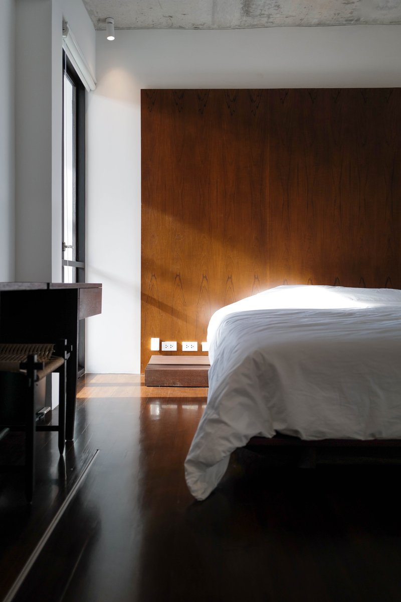 Bedroom with timber paneled wall illuminated by morning sunlight from a narrow window
