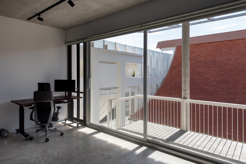 Interior workspace with sliding glass doors opening to a balcony with white slatted railing and brick wall beyond