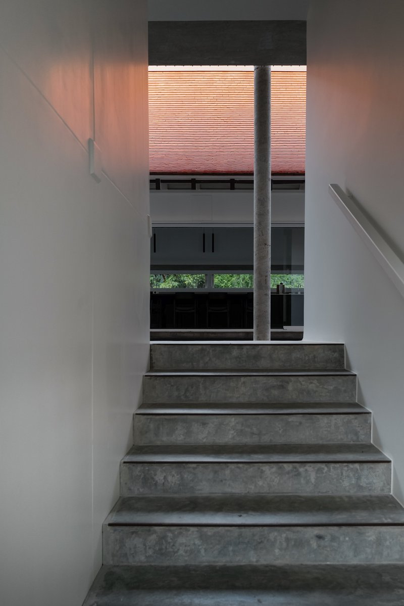 Stairwell with concrete steps ascending toward window with pink terracotta screen filtering warm afternoon light