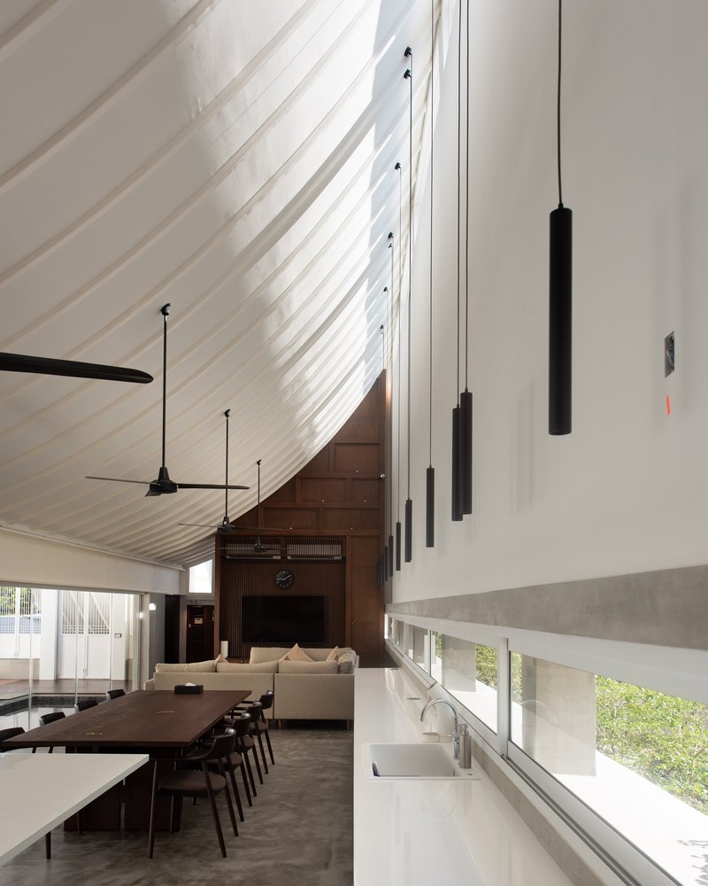 Double-height dining area with white ribbed ceiling, black pendant lights and horizontal window band