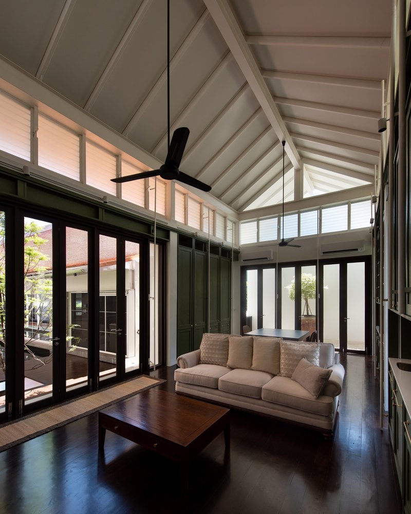 Living room with vaulted white ceiling, black-framed glazed doors opening to courtyard and ceiling fan