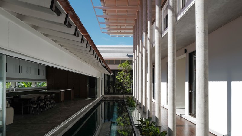Central courtyard with narrow reflecting pool flanked by white columns under timber slatted pergola
