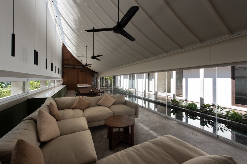 Interior living space with ribbed white ceiling panels, exposed timber beams, and black pendant lights