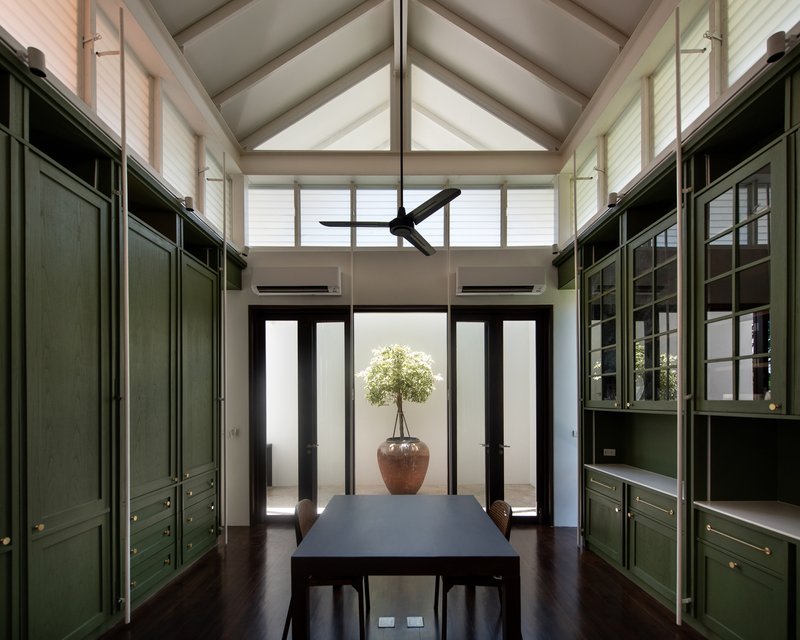 Dining room framed by green built-in cabinetry beneath a vaulted ceiling with clerestory windows