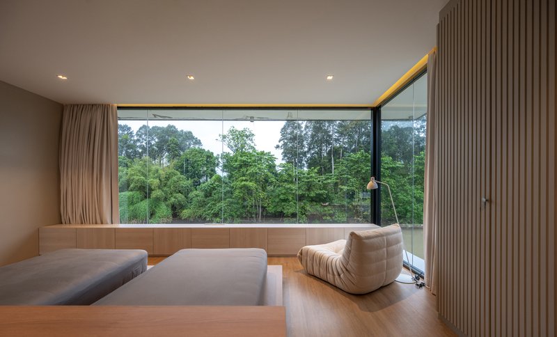 Interior lounge with floor-to-ceiling glazing overlooking the forested landscape at dusk