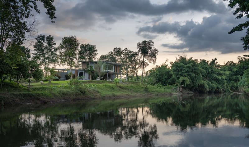 Riverbank view of the residence under dramatic clouds with water reflection