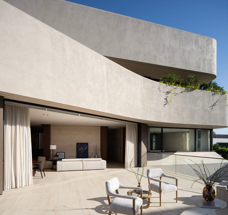 Cantilevered upper terrace with planted edge above open living room with floor-to-ceiling glazing and seating