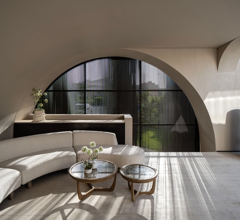 Interior living room with arched black-framed window casting striped shadows across the polished floor