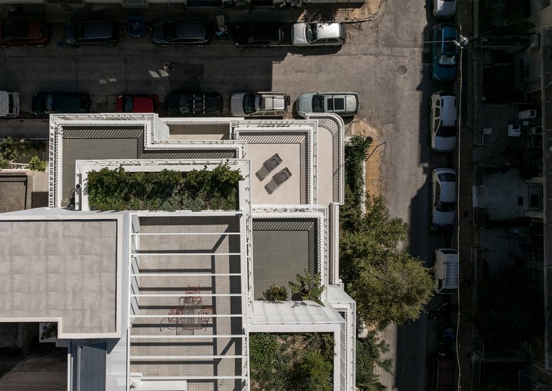 Drone view of the staggered rooftop terraces with planted beds and furniture overlooking parked cars