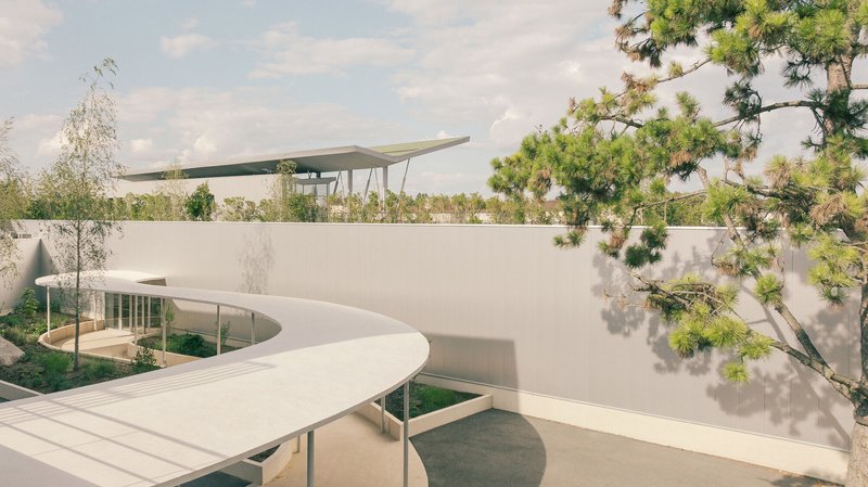 White curved canopy extending over courtyard with circular opening and pine tree casting shadows