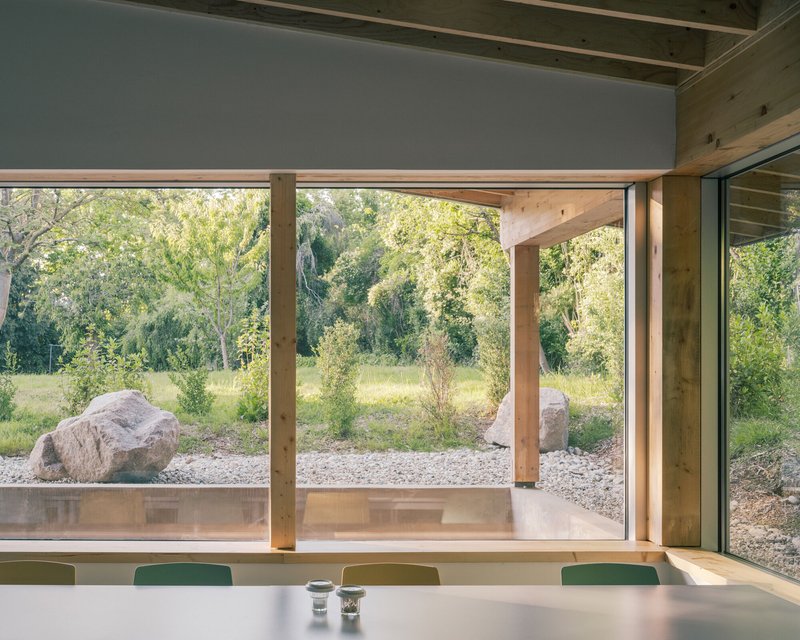 Corner window seat overlooking timber posts and boulders in the gravel garden beyond