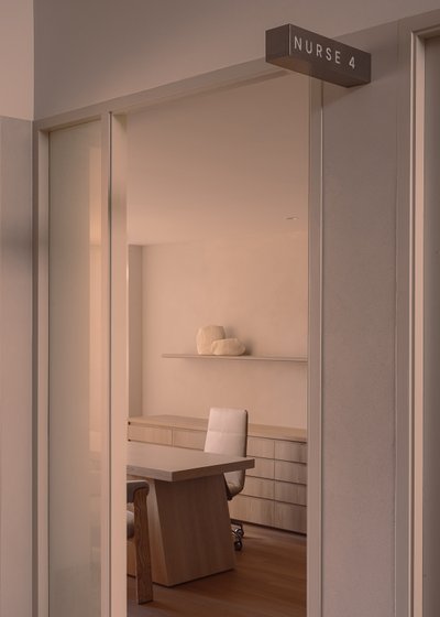 The image showcases a modern, minimalist office space, likely a nurse's station, viewed through a do