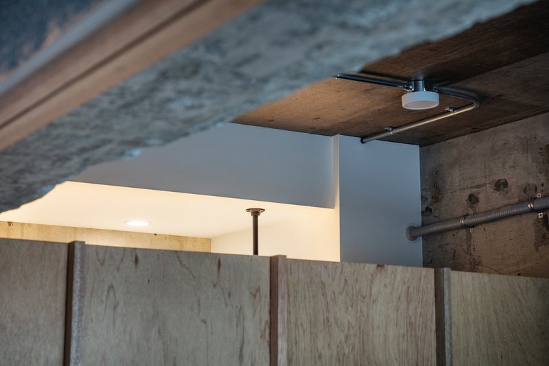 Detail of plywood panel edge meeting concrete beam with slim task light mounted above