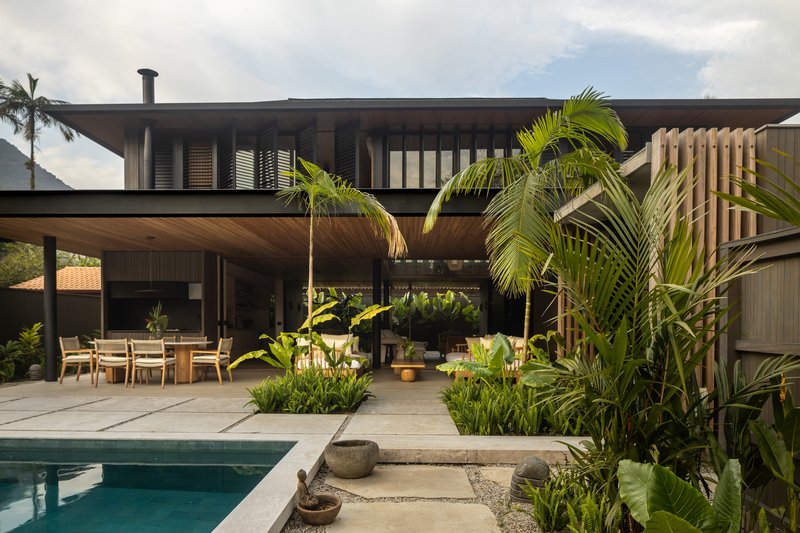 Poolside terrace with planted beds beneath the overhanging timber soffit and upper floor balcony