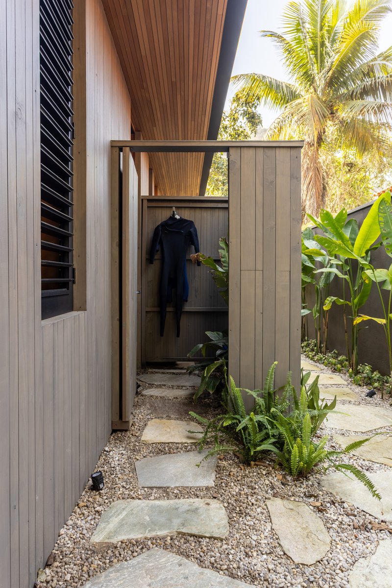 Gravel pathway with stepping stones leading to an outdoor shower with timber-clad walls and a wetsuit