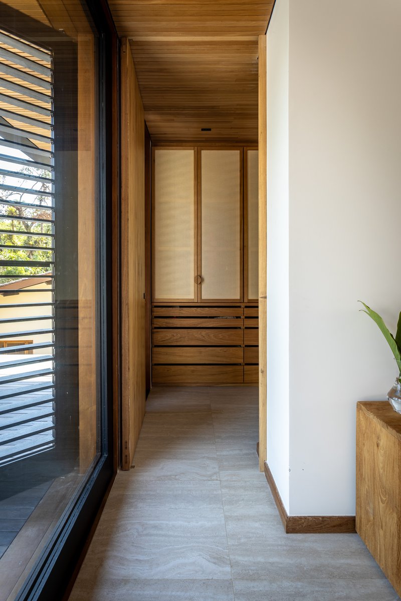 Narrow corridor with timber ceiling and built-in wardrobe with louvered sliding doors at the end