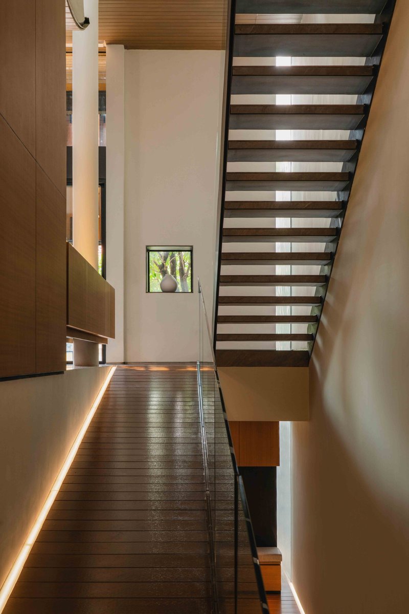 Open timber tread staircase with glass balustrade and suspended wood millwork alongside the landing