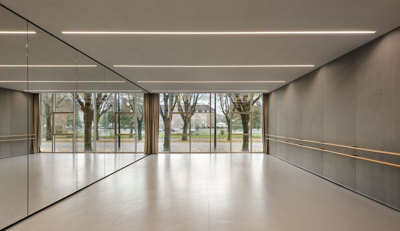 Dance studio with mirrored wall and horizontal light strips overlooking trees in a park