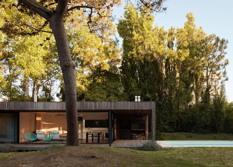 Garden facade with full-height glazing and firewood storage alcove at dusk