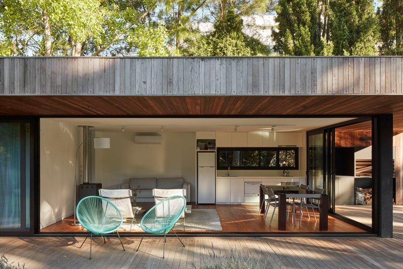 Open-plan living space with timber deck terrace and diagonal wood ceiling detail