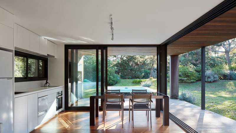 Interior dining area with floor-to-ceiling glazing overlooking the garden and pool