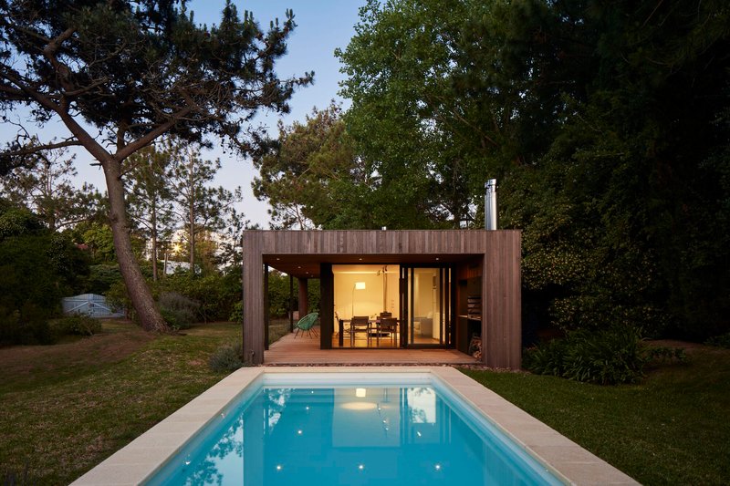 Rear elevation with illuminated interior and reflecting pool at twilight
