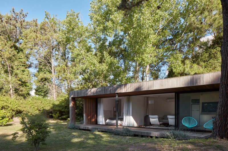 Garden view of the single-storey volume with sliding glass walls and timber-decked terrace
