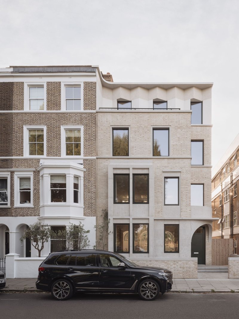 Street facade showing pale brick infill between traditional brick rowhouses with a parked car in front