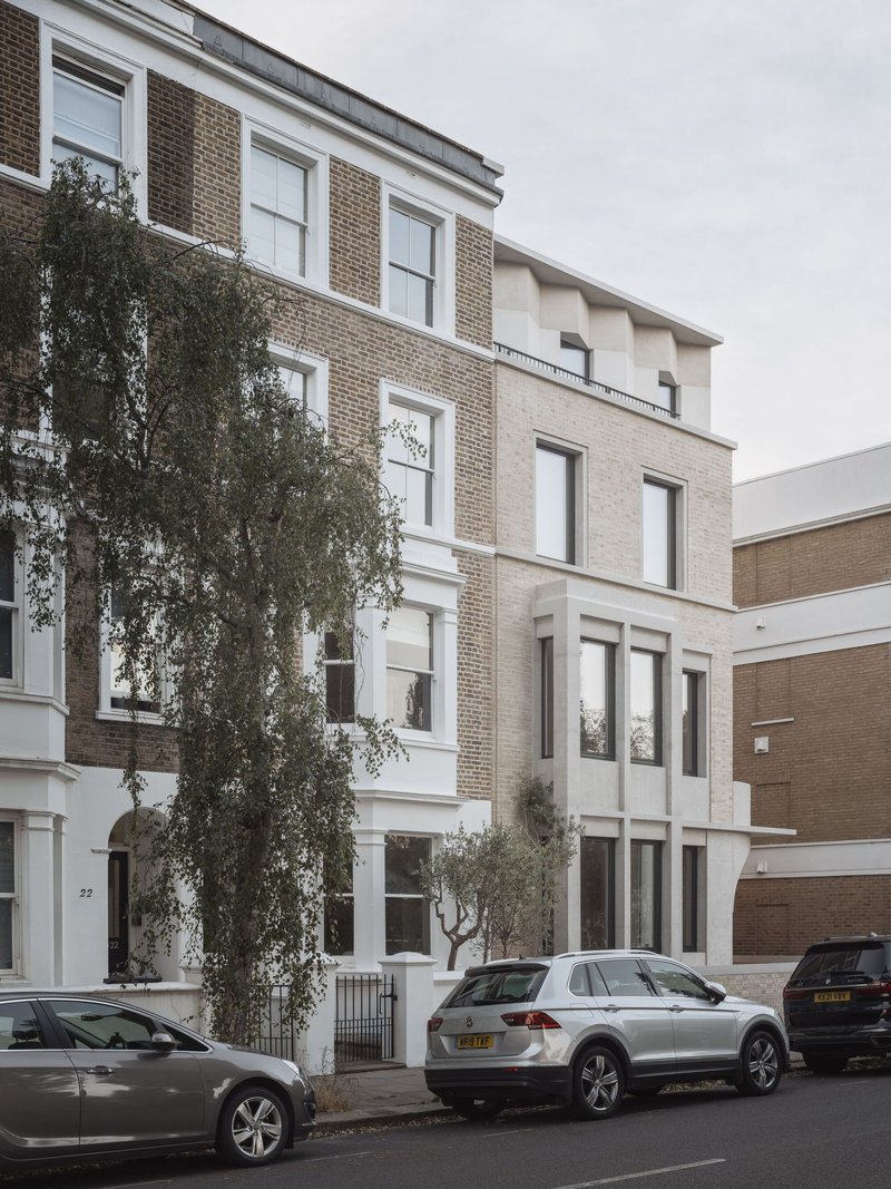 Street view of the four-storey brick facade with a mature tree growing at the entrance