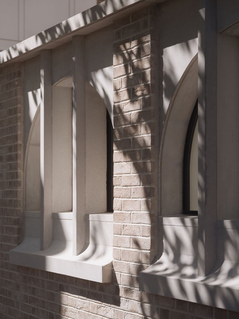 Close-up of the white balustrade casting sharp shadows on pale brick beneath afternoon sun