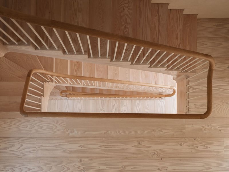 Top-down view of timber staircase with curved handrail and vertical slat balustrade