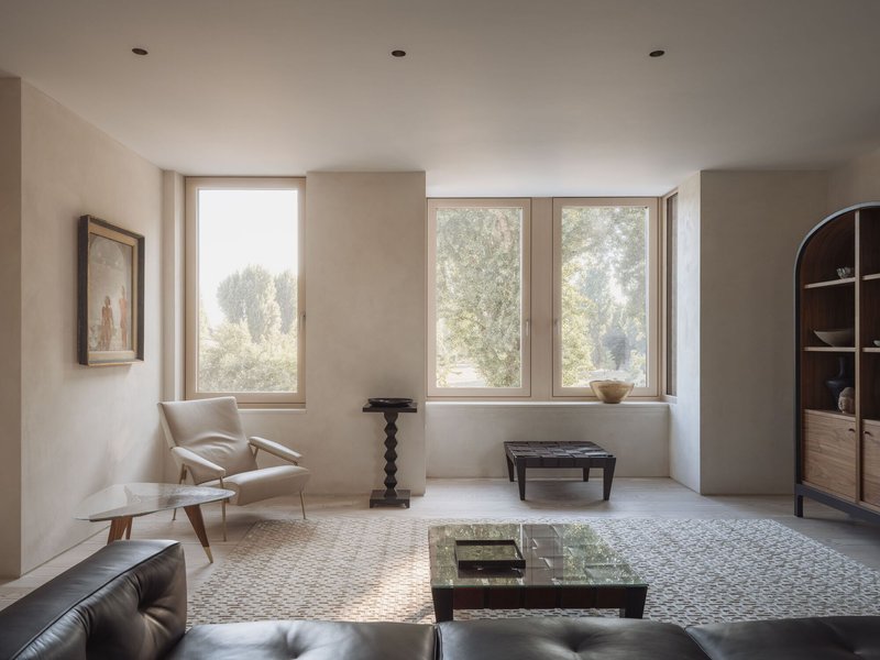 Living room with three large windows overlooking misty trees and a pebble mosaic floor