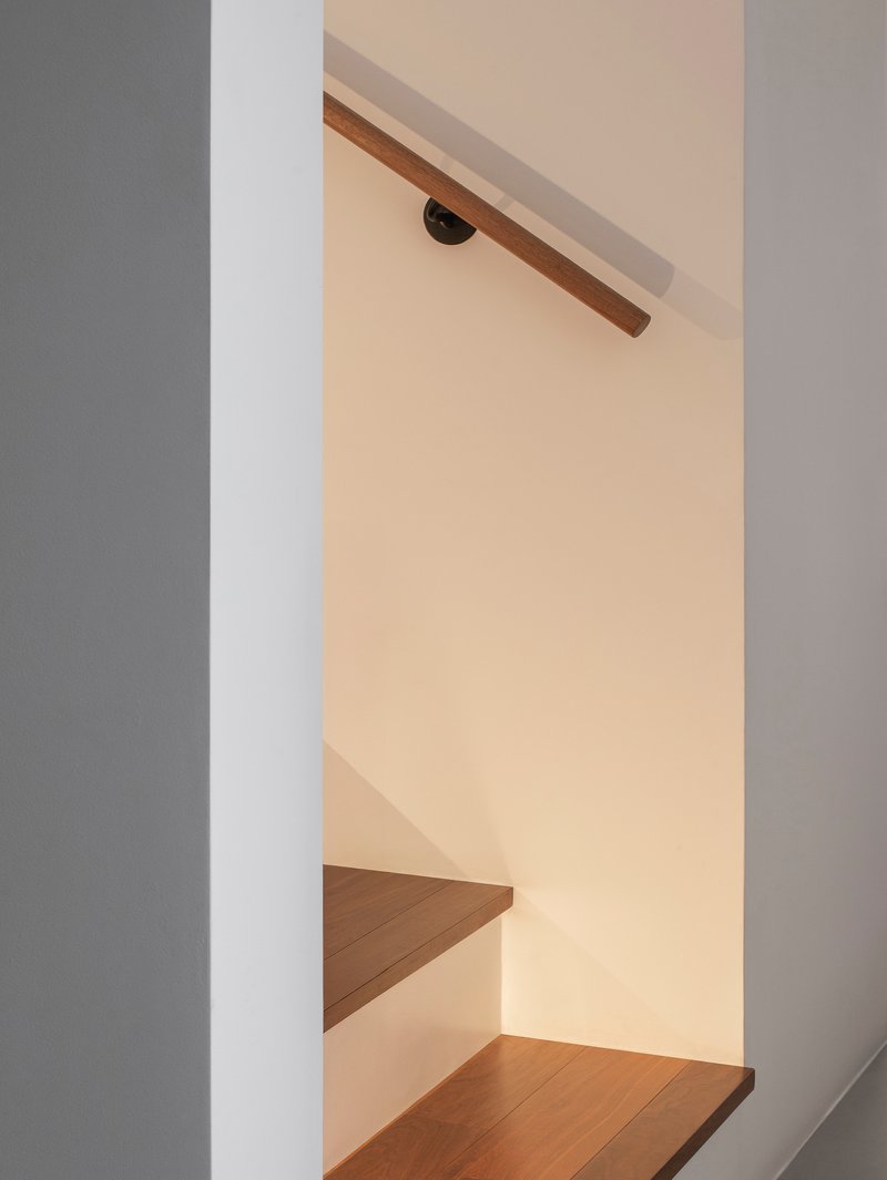 Detail of timber handrail meeting wall bracket beneath warm ambient lighting
