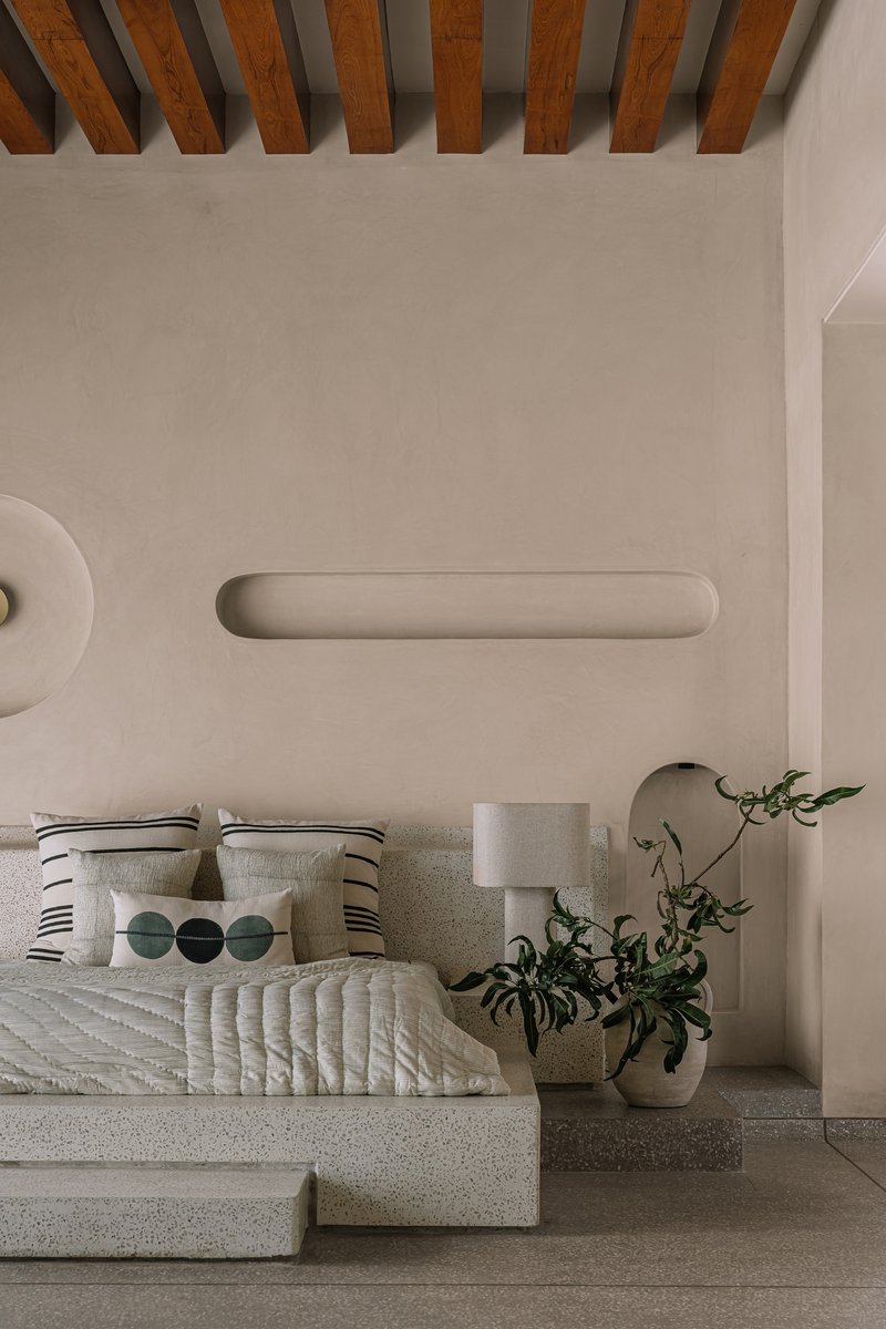 Low platform bed beneath exposed timber joists and recessed wall lighting slots