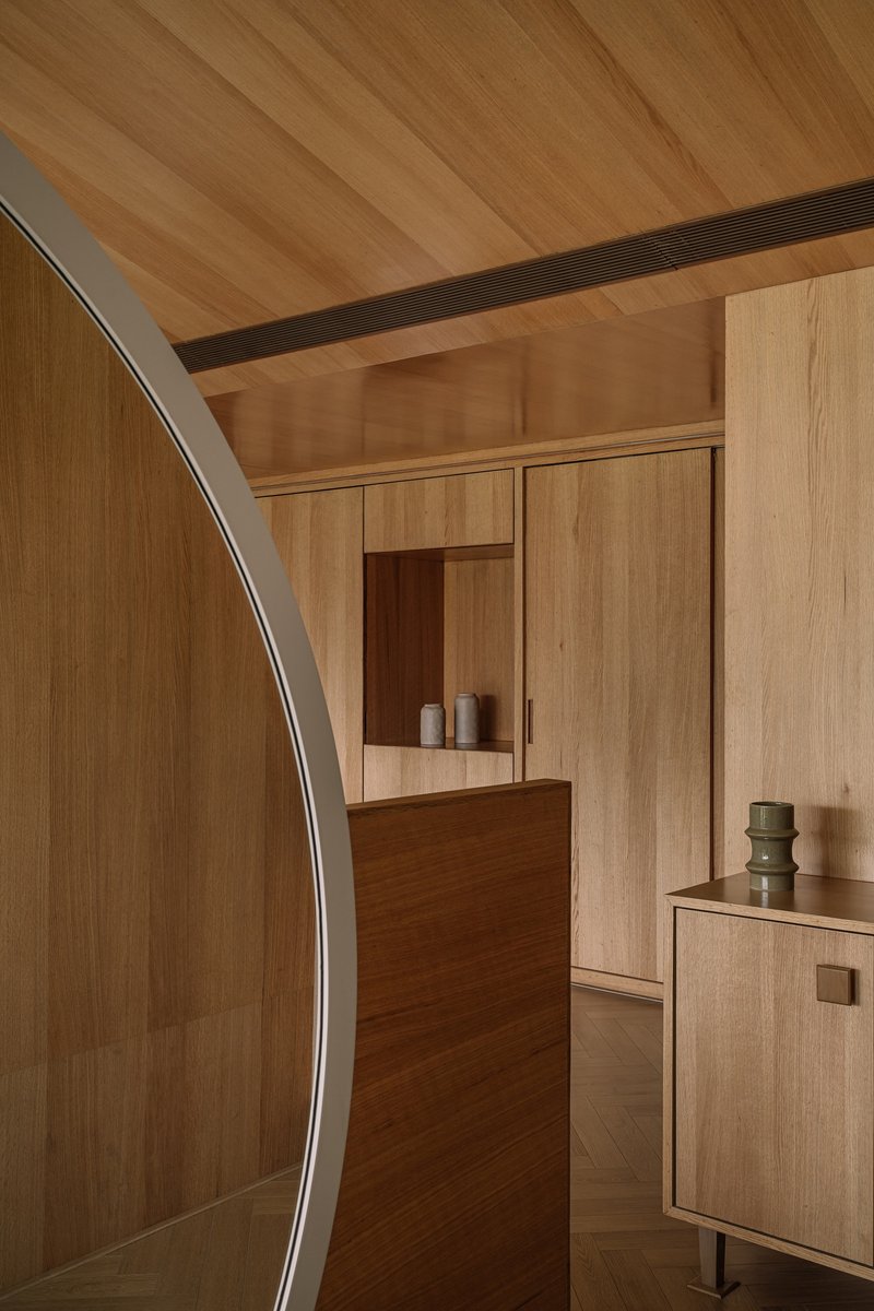 Timber-lined corridor with curved wall, built-in cabinetry and exposed wood ceiling joists