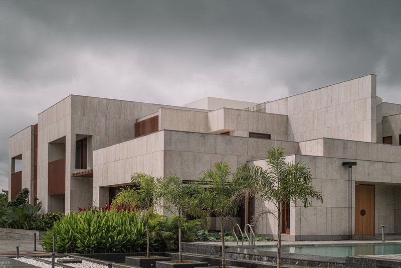 Rear facade with stacked concrete volumes overlooking a pool with palms and tropical plantings