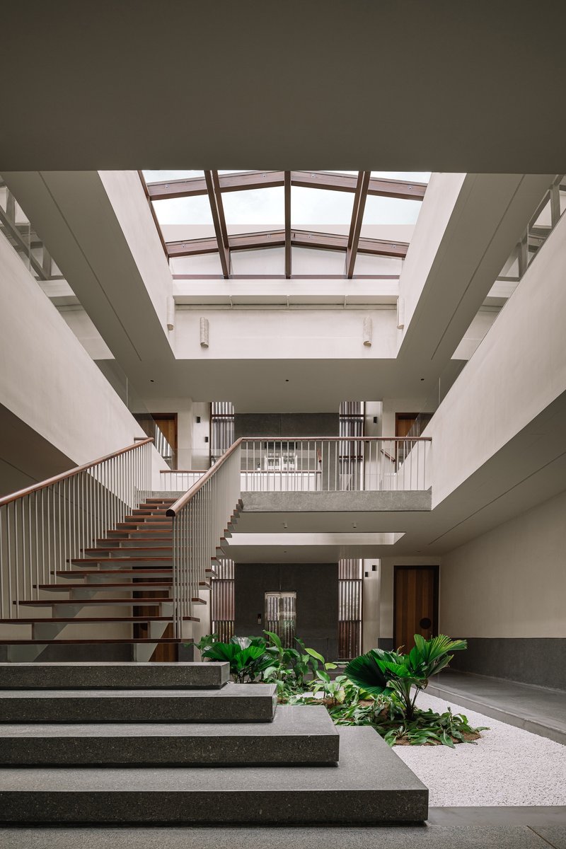 Triple-height entry hall with floating staircase and clerestory skylight above planted courtyard beds
