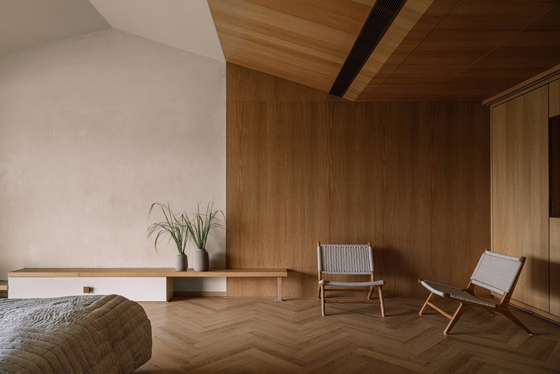Living room with herringbone timber flooring and angled wood-paneled ceiling with exposed beams