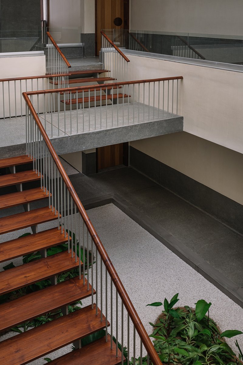 Top-down view of open stairwell showing intersecting timber treads and metal railings over multiple levels