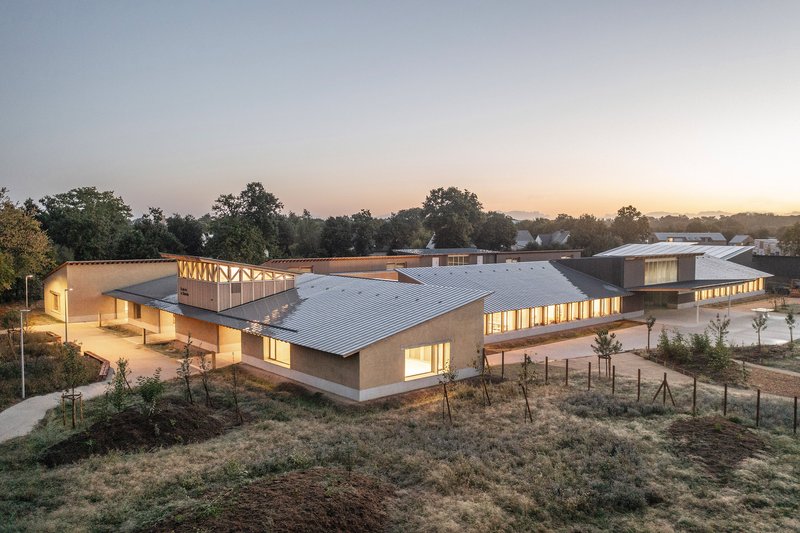 Aerial view of the campus with gabled roofs and illuminated interiors at dusk