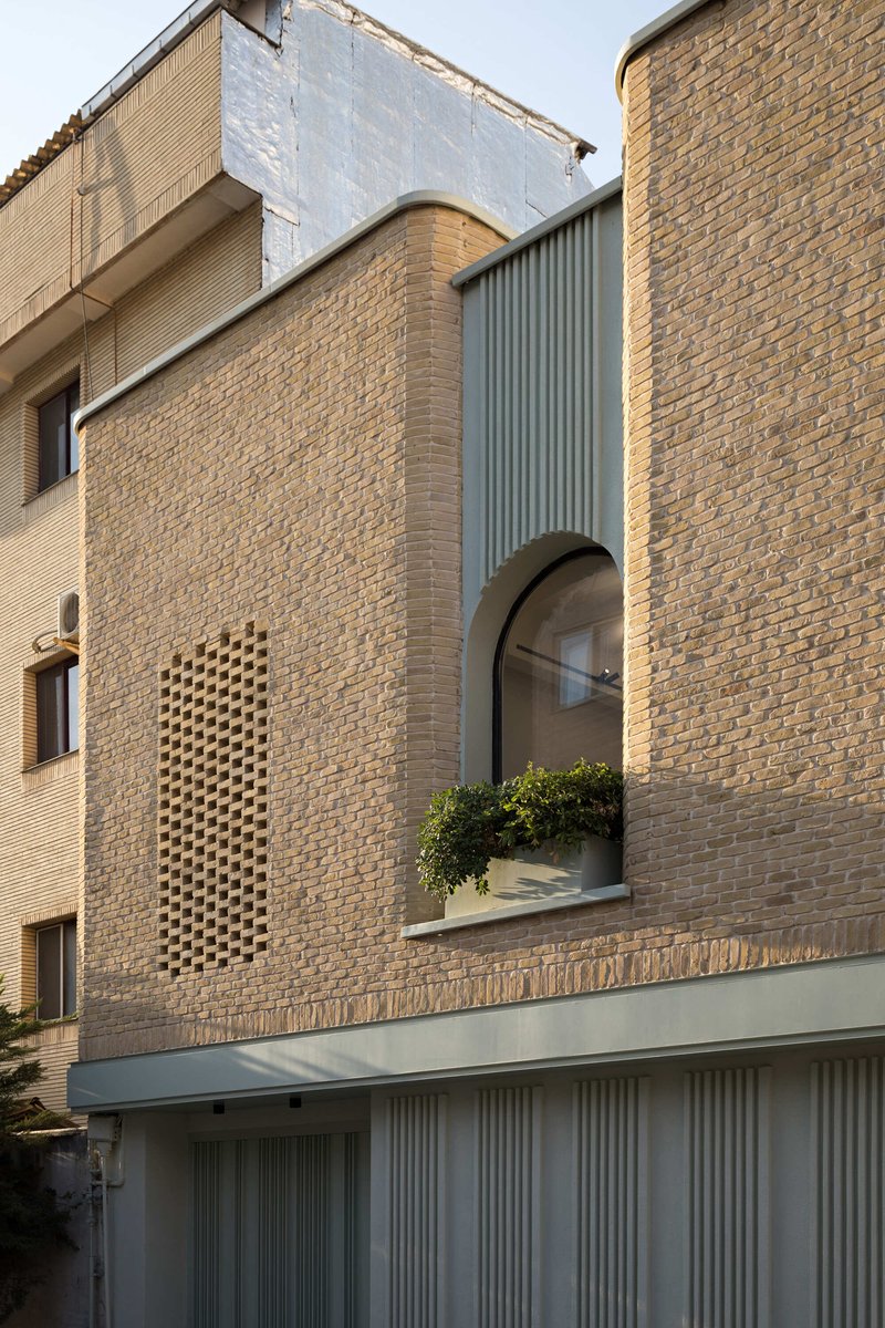 Close-up of the arched window niche and latticed brick opening with planter box on the facade