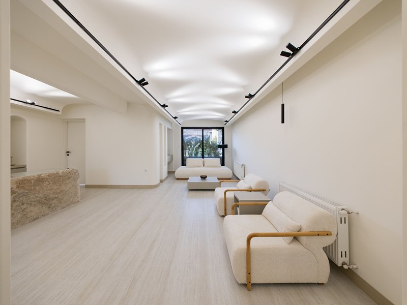 Long interior space with light timber flooring and continuous black track lighting along the ceiling