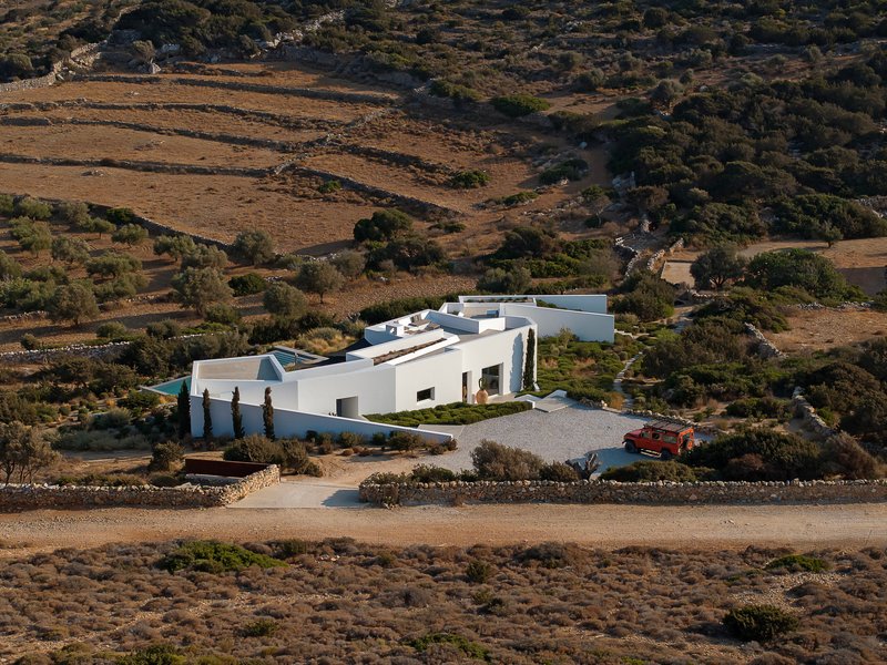 White compound nestled in a hillside landscape with terraced fields and sparse vegetation