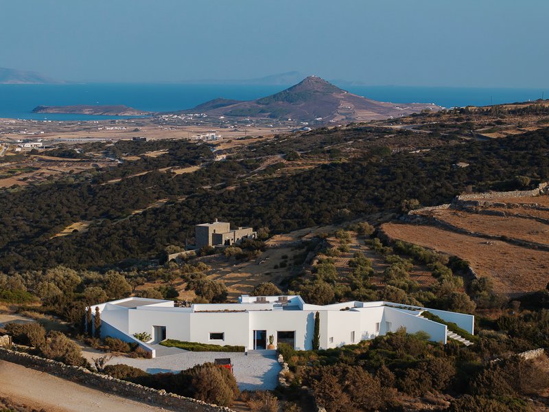 Aerial view of the white rendered residence among dry scrubland with coastal mountains in the distance