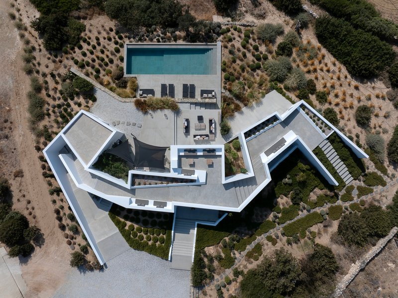 Drone view showing the angular white roofscape with central courtyard pool and surrounding olive groves