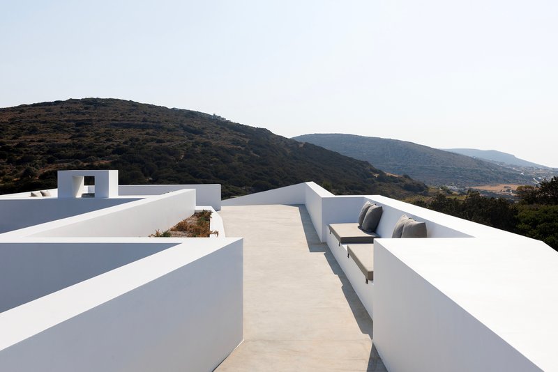 Rooftop terrace with white plastered parapets and built-in seating facing mountain ridgelines
