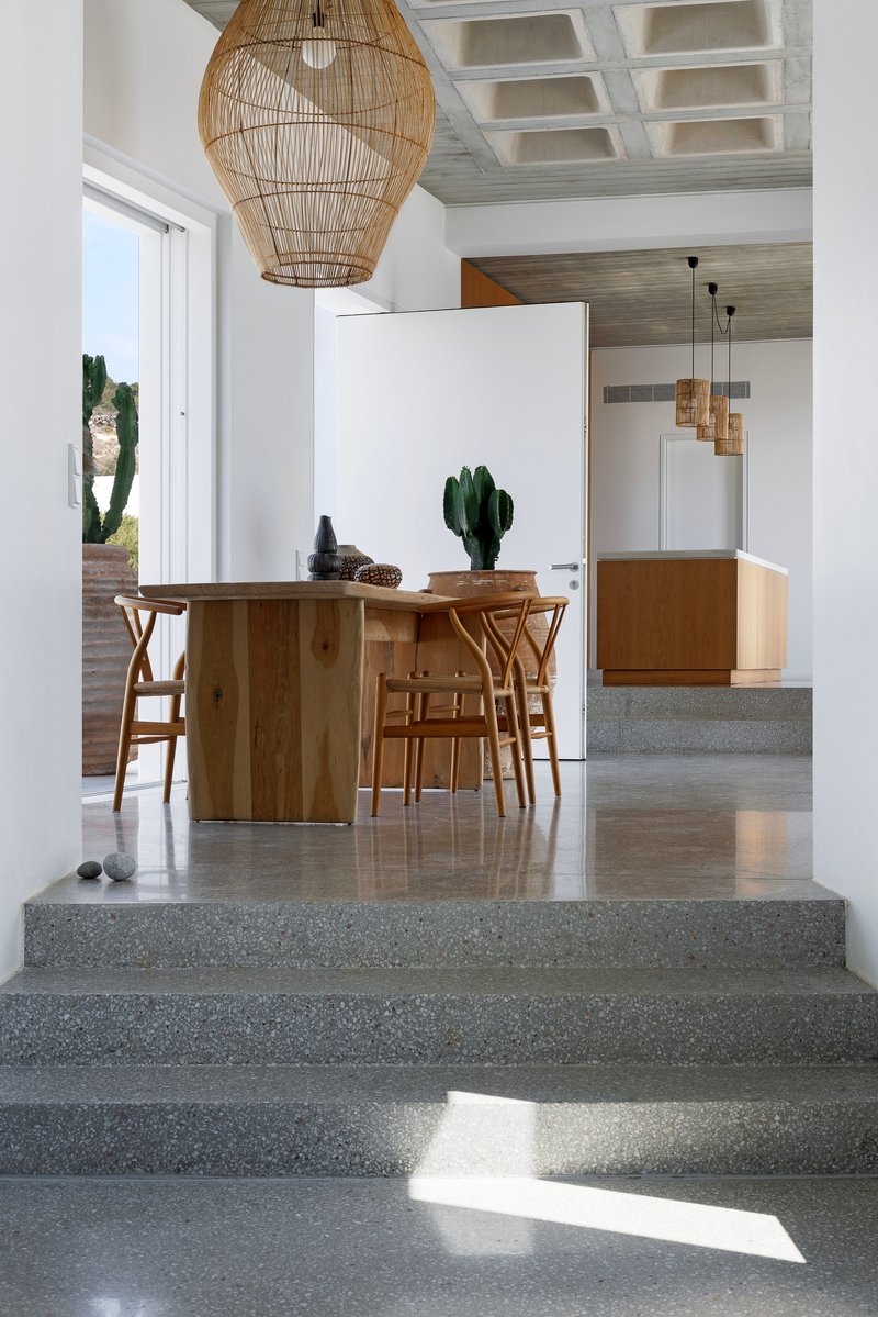 Polished terrazzo steps leading to the dining area with wooden table and woven pendant lights