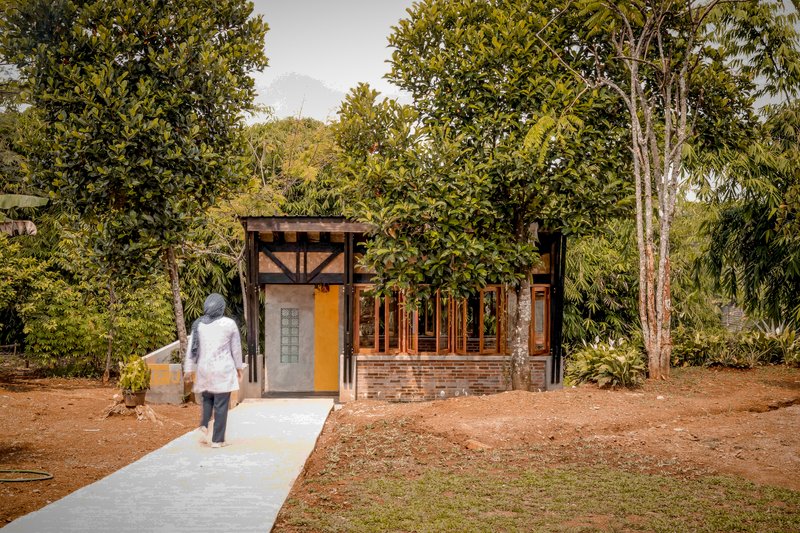Front approach with concrete path leading to the yellow door as a visitor walks toward the entrance