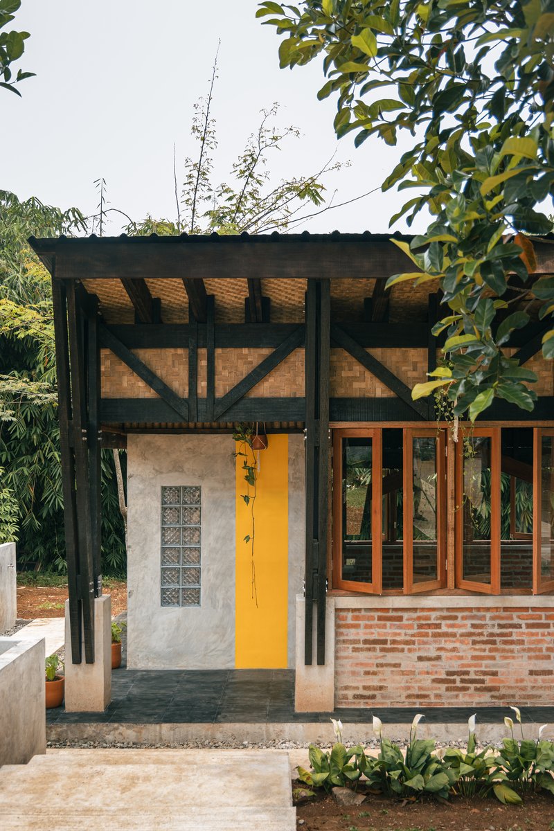 Entry facade showing the yellow door, glass block window and exposed diagonal bracing under the overhang